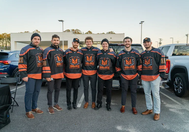 Members of the Fayetteville Marksmen hockey team standing in front of the Flow Buick GMC dealership…